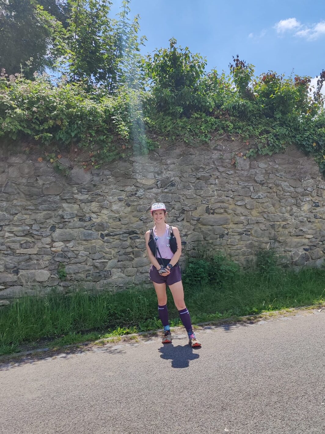 Christina in voller Trail-Runner-Montur vor eine Mauer
