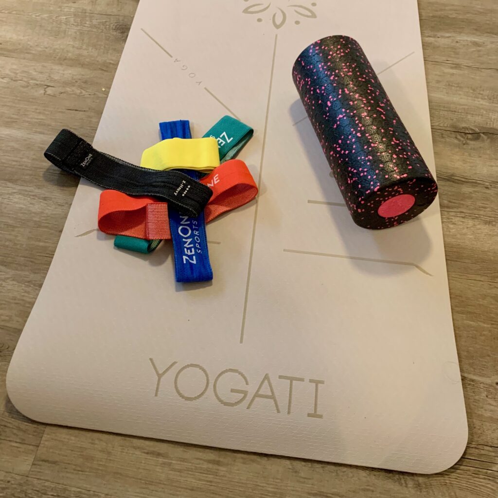 Yogamatte mit Widerstandsbändern und einer Faszienrolle.
